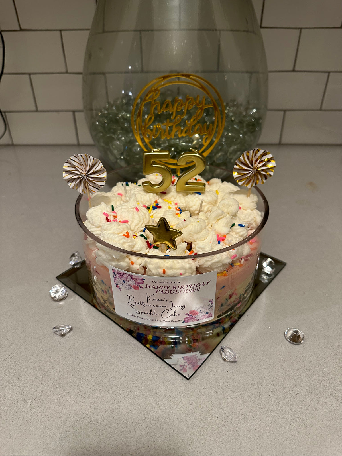 Extra large custom birthday cake candle with 'Happy Birthday' and decorative toppers on a countertop.