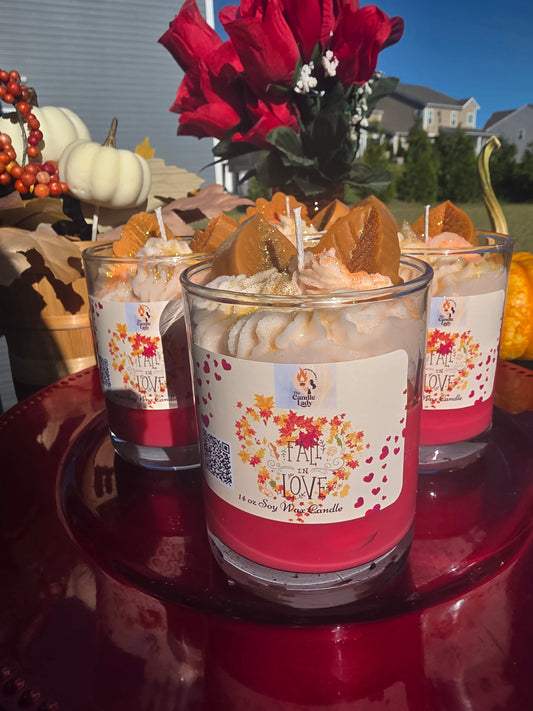 Three candles with fall-themed labels on a red surface outdoors.