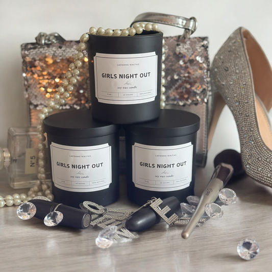 Three 'Girls Night Out' candles with decorative items on a surface