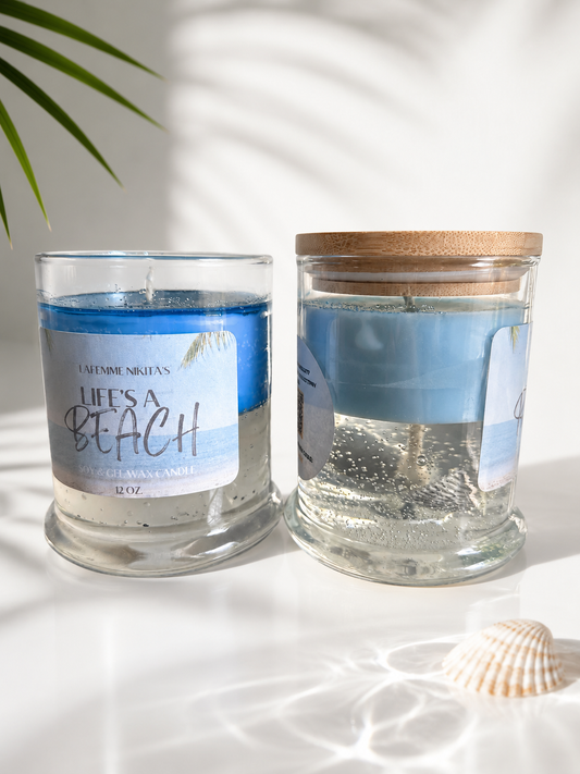 Two soy and gel wax candles displayed with sea shells and beach like decor