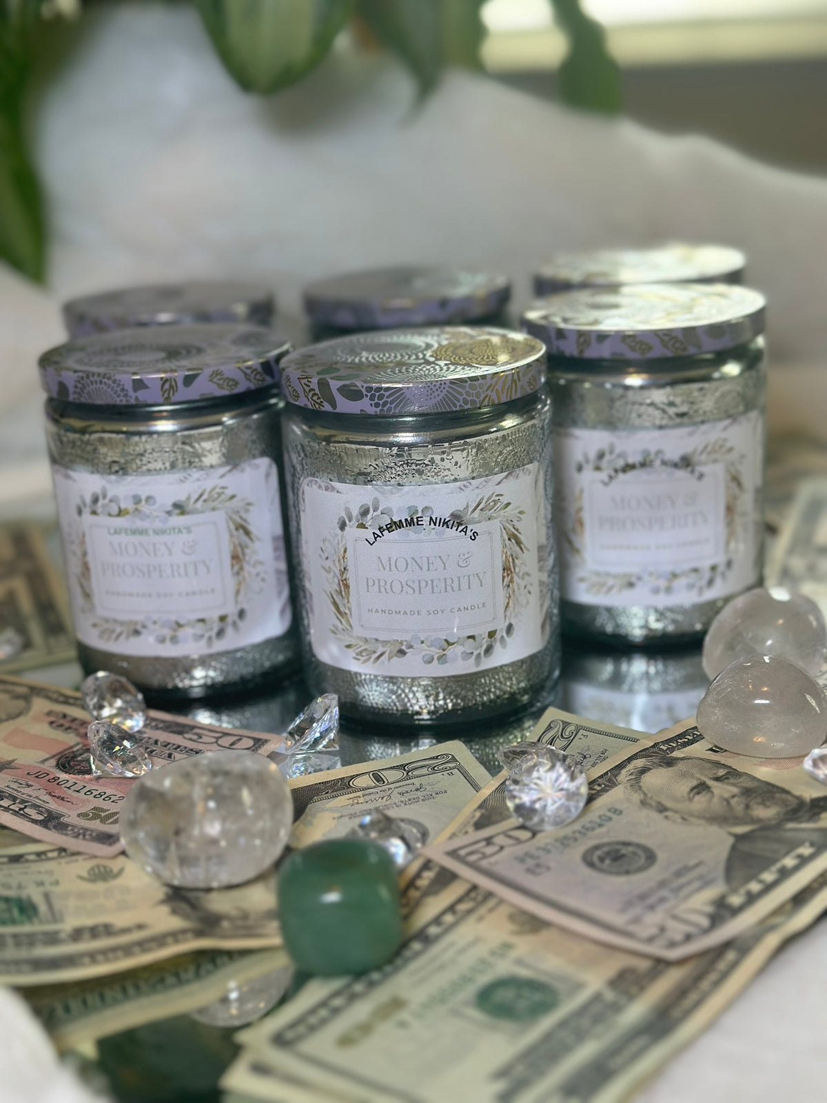 Decorative candles made with soy wax. Displayed on top of dollar bills and crystals on a reflective surface