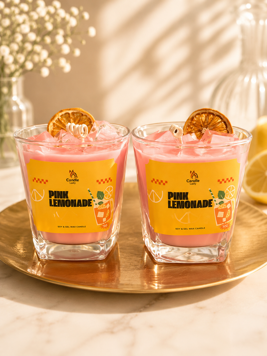 Two glasses of pink lemonade soy wax candles sitting on a table