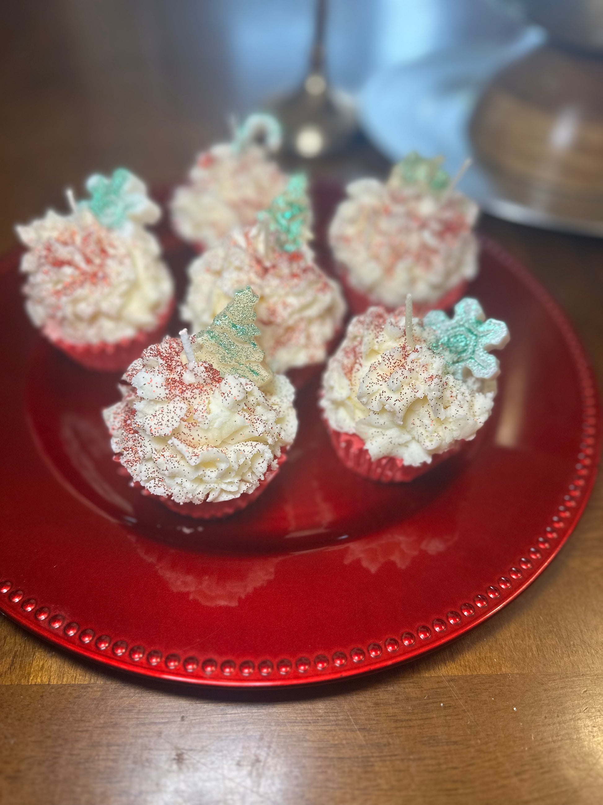 Decorative cupcake candles made with soy wax on a red plate with a blurred background