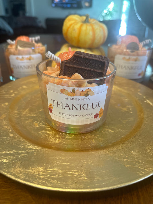 Candle labeled 'Thankful' on a gold plate with pumpkins in the background