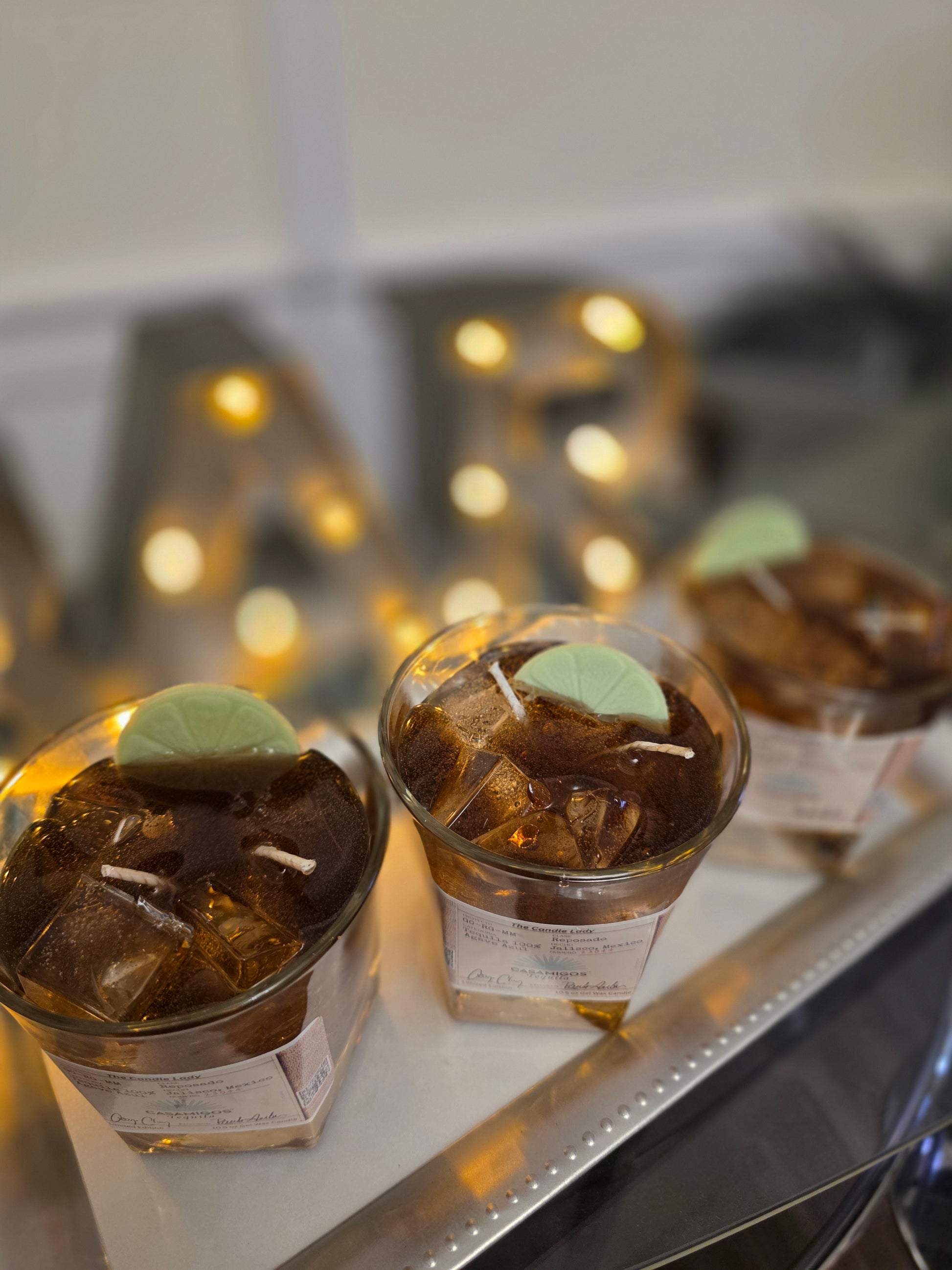 Three small jars with candles on a surface with blurred lights in the background