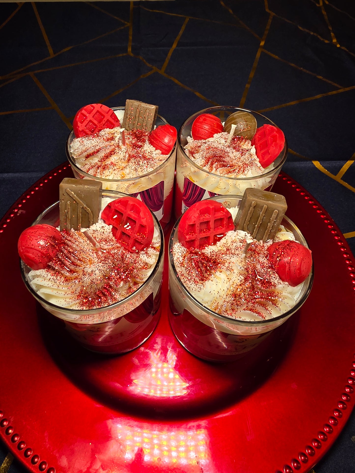 Three dessert candles with red and white toppings on a red plate.