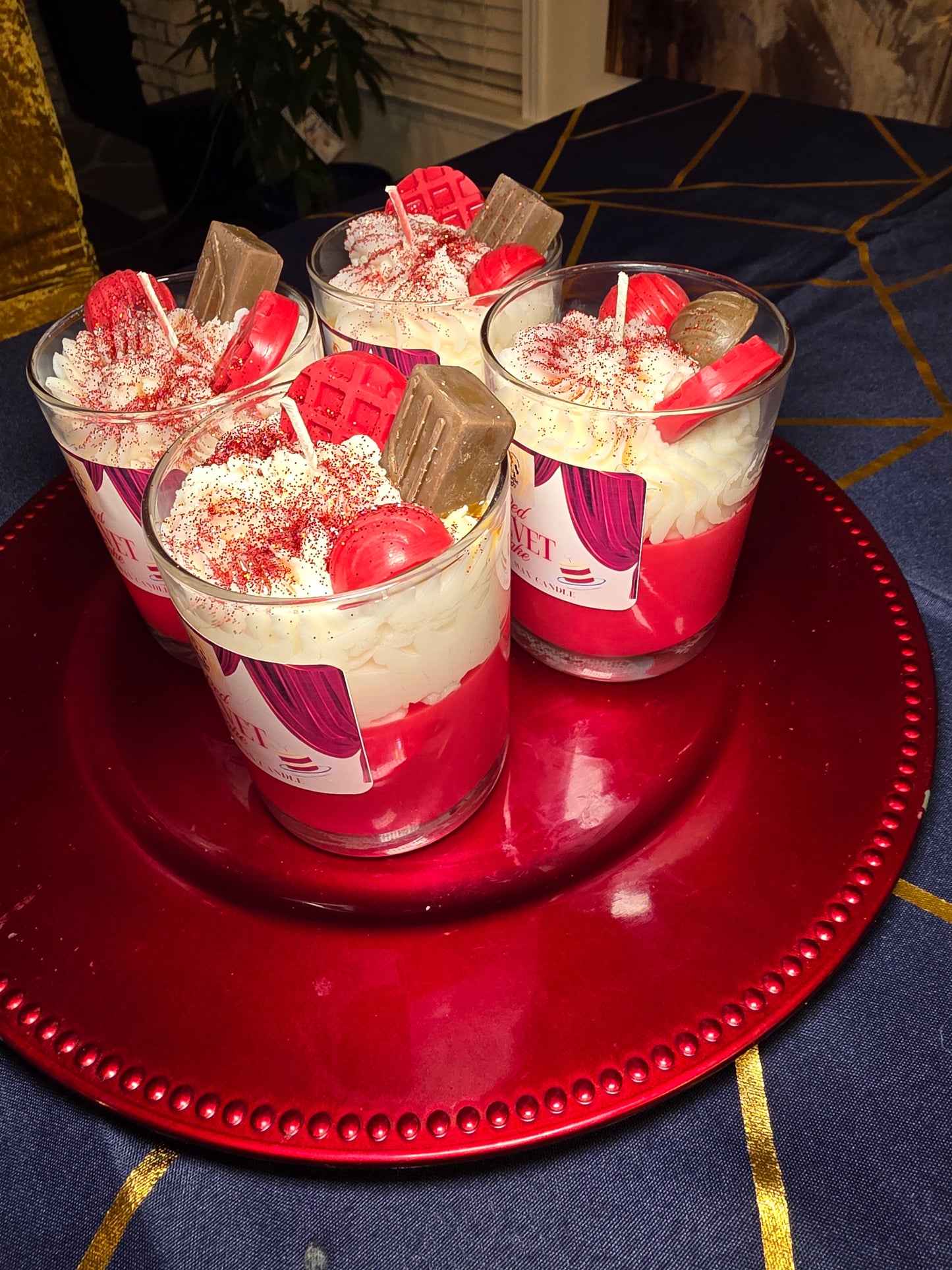 Two red velvet cake candles  on a red plate with a blue and gold patterned background