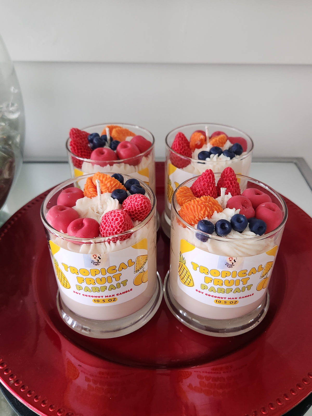 Two containers of candle wax fruit on a red surface
